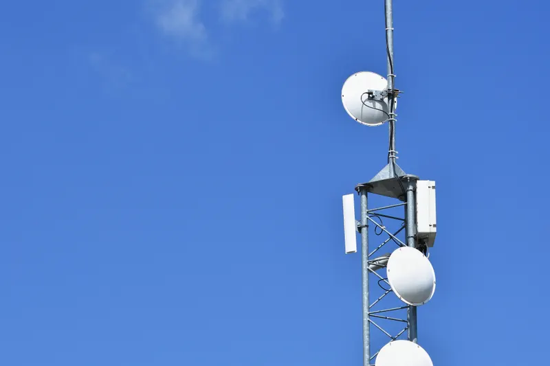 A telecommunications mast with dish antennas against a clear sky
